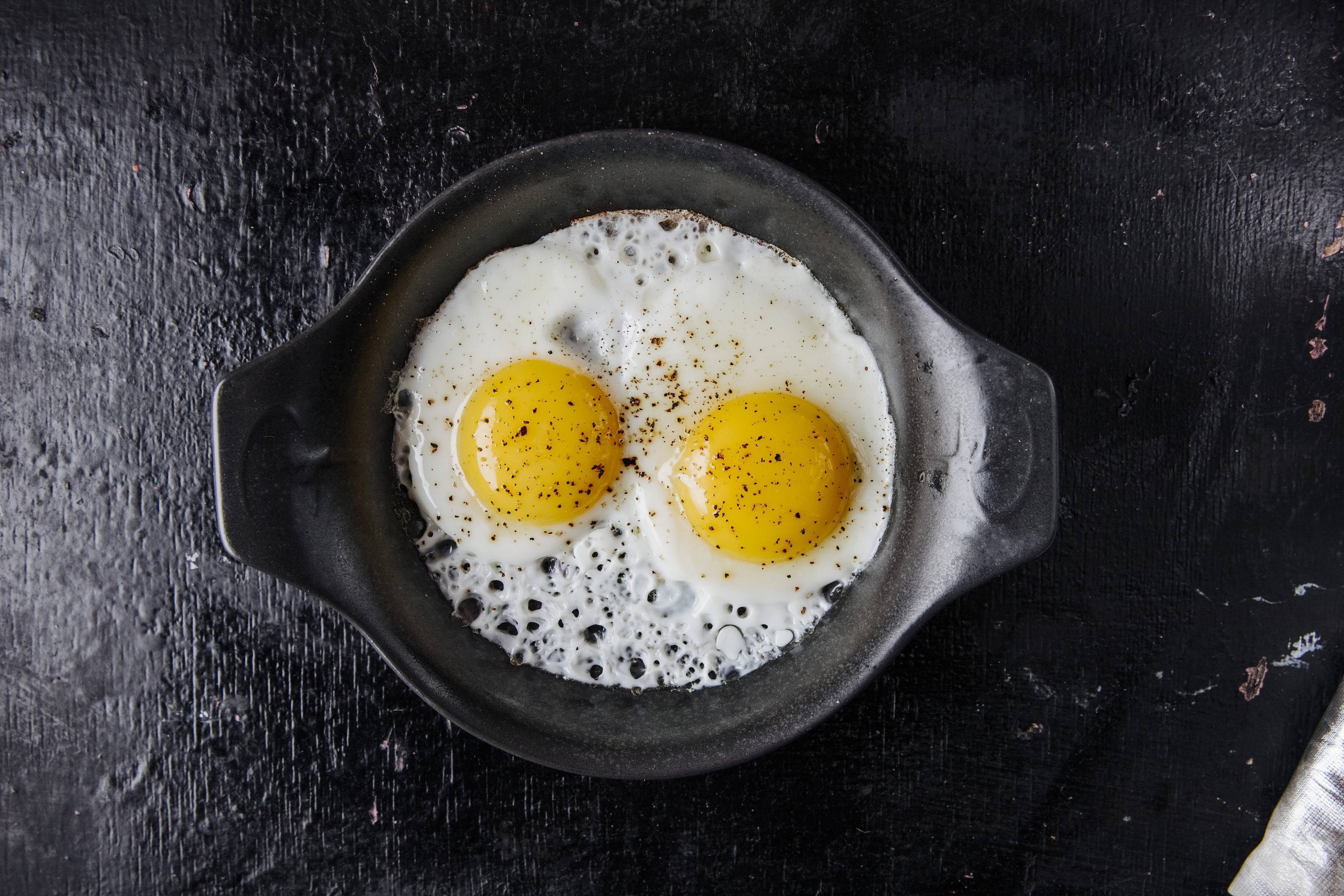 Яйцо сверху. Серое на жареных яйцах. Крест жареное яйцо. Fried Egg Top view. Happy girl Fried Eggs on a Pan.